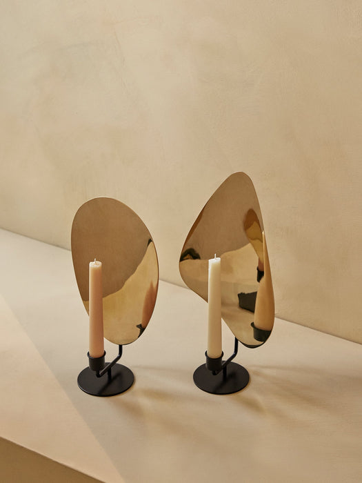 A pair of Flambeau Candle Holders with black bases and polished brass reflectors. One holds a pink candle, the other white.