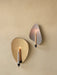 Two Flambeau Wall Candle Holders, brass and steel, mounted on a textured beige wall with lit candles casting a warm glow.