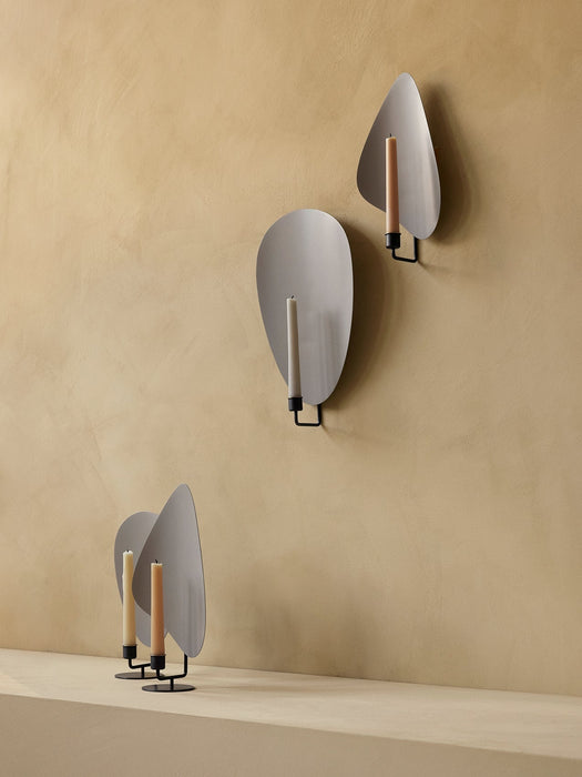 A collection of Flambeau Candle Holders, with two standing on a shelf and two mounted on a warm, textured wall behind them.