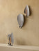 A collection of Flambeau Candle Holders, with two standing on a shelf and two mounted on a warm, textured wall behind them.