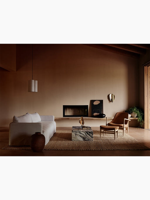 Warmly lit living room with an Offset Sofa, Hashira Cluster lamp, Plinth Low table, and Elizabeth Lounge Chair with Ottoman.