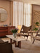 A stylish living room with two sheepskin Knitting Chairs, a low marble coffee table with a vase, and a wooden sideboard.