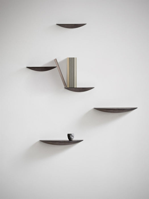 A group of five dark oak Gridy Fungi Shelves mounted on a white wall, styled with a book and a small ceramic cup.