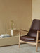 Side view of The Seal High Back chair in brown leather. Nearby, a cream Hana Vase with flowers sits on a ledge with books.