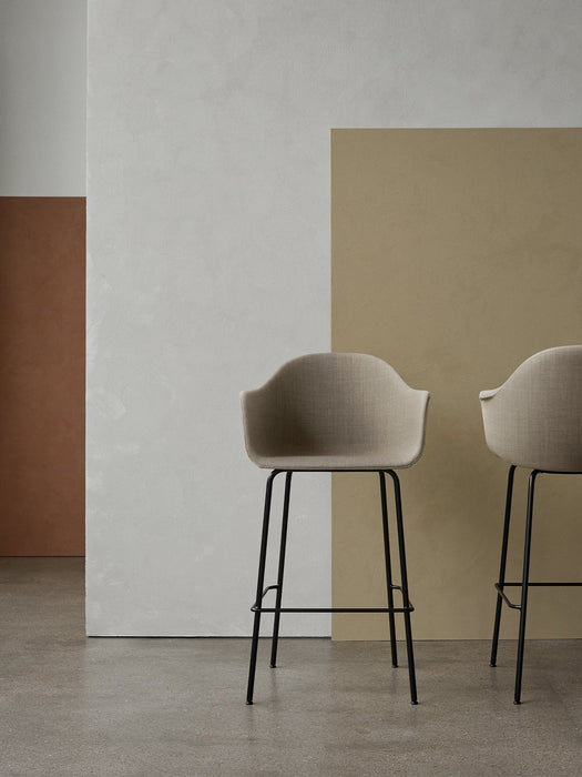 Two beige upholstered Harbour Bar Chairs with black steel frames stand in a minimalist room with colour-blocked walls.