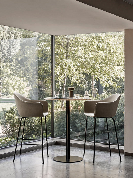 Two Harbour Bar Chairs in light grey upholstery sit at a marble bar table before a large corner window with a garden view.