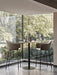 Two Harbour Bar Chairs in light grey upholstery sit at a marble bar table before a large corner window with a garden view.