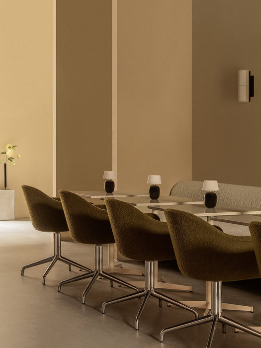 A row of olive green Harbour Dining Chairs with polished star bases set at Nook Dining Tables with portable Torso Table Lamps