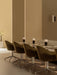 A row of olive green Harbour Dining Chairs with polished star bases set at Nook Dining Tables with portable Torso Table Lamps