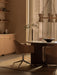 A warmly lit dining room featuring brown Harbour Dining Chairs with polished star bases pulled up to a dark Androgyne Table.