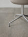 A close-up of the Harbour Dining Chair's polished aluminium star base, with its four legs on a grey terrazzo floor.