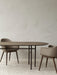 Two Harbour Dining Chairs with wooden legs sit at a Snaregade Oval Dining Table on a striped Houkime Rug in a minimal room.
