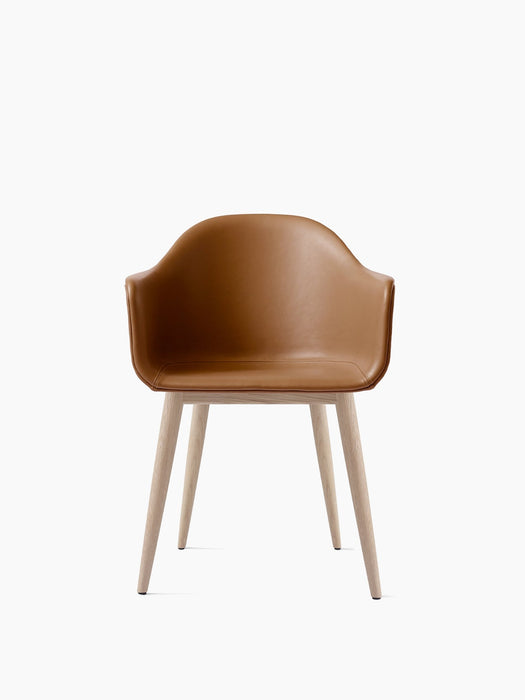 Front view of the Harbour Dining Chair featuring a contoured tan leather shell with integrated armrests and natural oak base.