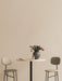 A Harbour Column Bar Table with a marble top, flanked by two beige Afteroom Bar Chairs. A vase of tulips decorates the table.