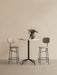 A marble-top Harbour Column Counter Table with a black star base, a vase of tulips and two Afteroom Counter Chairs.