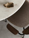 Overhead detail shot of the white marble Harbour Column Dining Table and brown upholstered Co Chair with dark wood armrests.