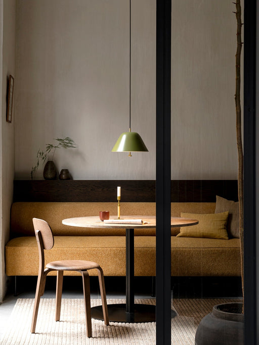 A Harbour Column Dining Table in a cosy dining nook, with a mustard banquette, wooden chair, and an olive green pendant lamp.