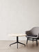 A Harbour Column Lounge Table with a light stone top and black star base, next to a grey upholstered Harbour Lounge Chair.