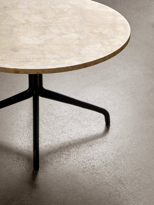 A close-up of the Harbour Column Lounge Table with a round Kunis Breccia stone top and a black star-shaped metal base.