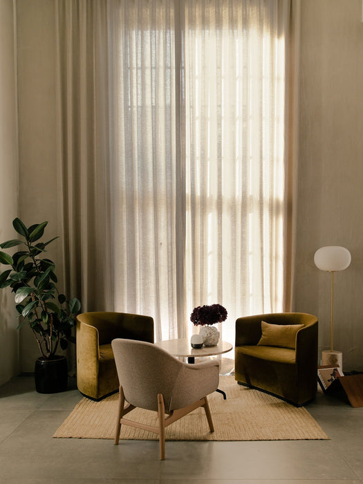 A Harbour Lounge Table between two olive Tearoom Lounge Chairs and a beige Harbour Lounge Chair in a bright, curtained room.