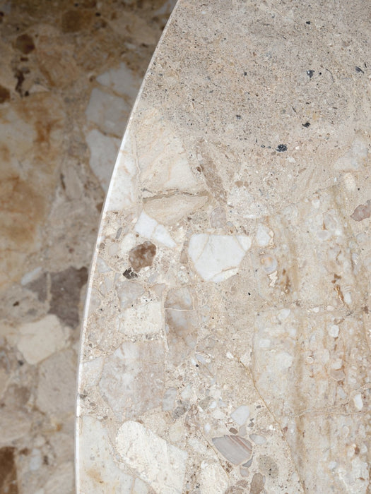 A close-up detail shot of the Harbour Column Lounge Table's round top, made from textured Kunis Breccia stone.