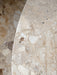A close-up detail shot of the Harbour Column Lounge Table's round top, made from textured Kunis Breccia stone.