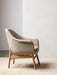 A Harbour Lounge Chair with light beige textured upholstery and a natural oak frame, side view in a minimalist room.