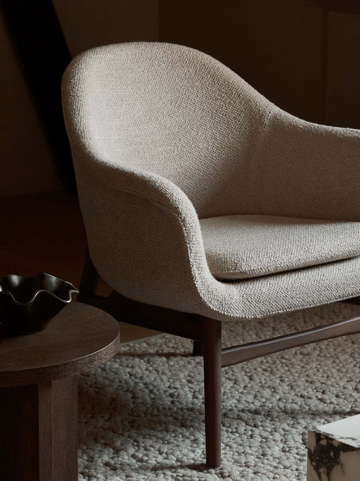 A close-up of the light, textured Harbour Lounge Chair on a Gravel Rug, next to an Androgyne Side Table with a Fragilis Bowl.