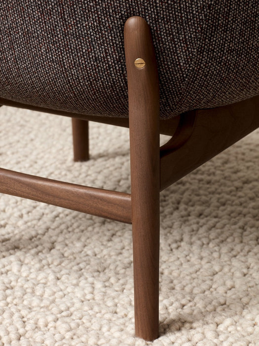 Close-up of the Harbour Lounge Chair's dark wood leg with a brass screw detail joining the textured brown fabric seat.