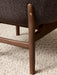 Close-up of the Harbour Lounge Chair's dark wood leg with a brass screw detail joining the textured brown fabric seat.