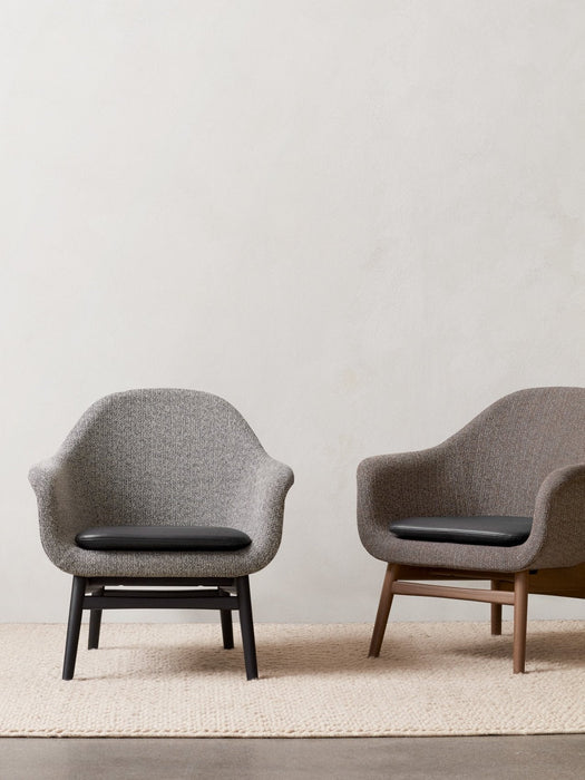 Two Harbour Lounge Chairs on a woven rug. One is grey with a black frame, the other is brown with a natural wood frame.