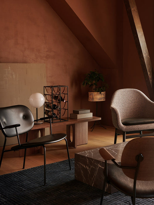 Harbour Lounge Chair in textured fabric, placed in a warmly lit room with terracotta walls, alongside a marble coffee table.