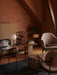 Harbour Lounge Chair in textured fabric, placed in a warmly lit room with terracotta walls, alongside a marble coffee table.