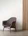 A brown fabric Harbour Lounge Chair with a dark wood frame and black cushion, set against a white wall and wood slat panel.