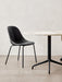 The Harbour Side Dining Chair, upholstered in black with a black steel base, sits beside a round marble dining table.