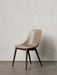 A Harbour Side Dining Chair with a beige leather upholstered shell and dark stained wooden base, against a plain wall.