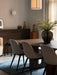 Side view of the Androgyne Dining Table and Harbour Chairs on a blue Houkime Rug, with a Tearoom armchair in the background.
