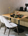 Two light-upholstered Harbour Side Dining Chairs with wooden bases at a dining table set for two, next to a yellow sofa.