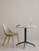 A beige upholstered Harbour Side Dining Chair with wood legs sits beside a marble-top table with a magazine and candlestick.