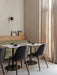 A restaurant corner featuring black leather Harbour Side Dining Chairs at white tables next to a green upholstered bench.