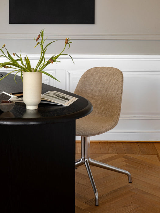 A Harbour Side Dining Chair with brown upholstery and a star base at a black table with a vase on a herringbone floor.