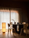 The Hashira Floor Lamp provides a warm glow in a dining room, beside an Androgyne Dining Table and Afteroom Plywood chairs.