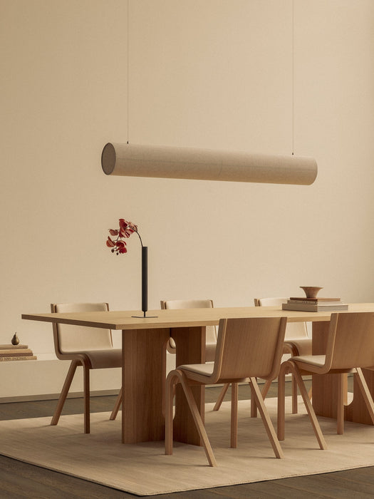 The Hashira Linear Pendant Lamp hangs over an Androgyne Dining Table set with Ready Dining Chairs and a Stance Vase.