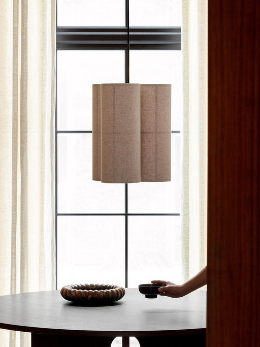 The Hashira Pendant Cluster lamp in Raw linen hangs above a dark wood Androgyne Dining Table with an NNWD Footed Bowl.