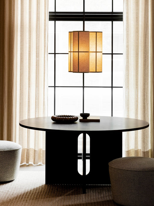 The Hashira Pendant Cluster lamp illuminates an Androgyne Dining Table with Cairn Poufs in a softly lit dining room.