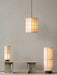 A Hashira Pendant Lamp Cluster, Floor Lamp and Table Lamp illuminate a minimalist room with a stone Androgyne Lounge Table.