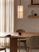 A Hashira Pendant Lamp illuminates an Androgyne Dining Table, Harbour Chairs, and Epoch Shelf in a warm, neutral dining room.