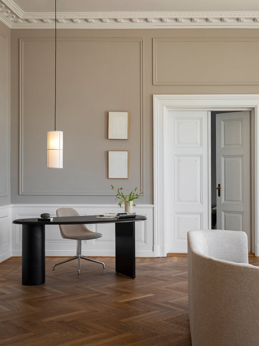 The Hashira Pendant Lamp hangs over a black desk in a classic office with herringbone floors and decorative moulding.