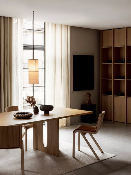 A Hashira Pendant Lamp hangs over an Androgyne Dining Table surrounded by Ready Dining Chairs in a minimalist dining room.