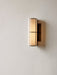 A close-up of the Hashira Wall Lamp with a raw linen shade, mounted on a light-coloured textured wall and emitting warm glow.